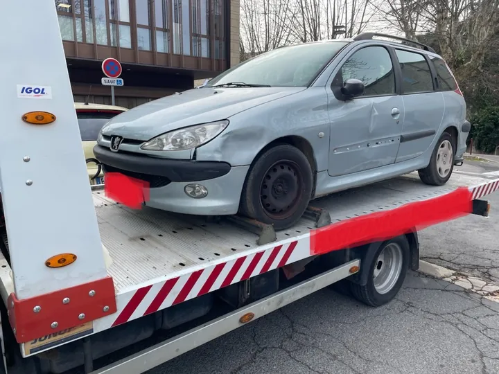 Voiture claire sur un plateau blanc, avec ses roues et sa carrosserie visibles.