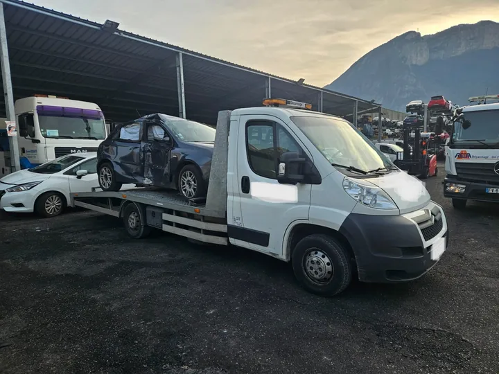 Voiture sombre aux éléments avant et latéraux endommagés sur un camion blanc.