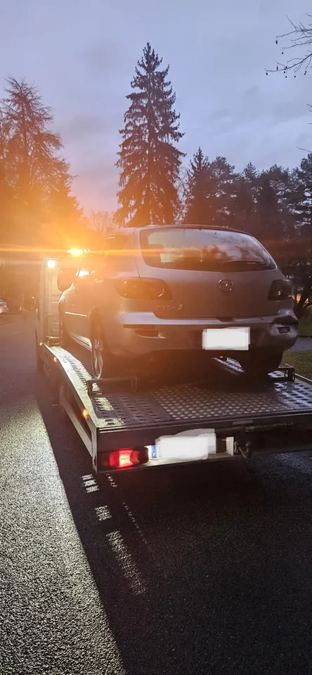 Arrière d’une voiture chargée sur un camion avec gyrophare orange allumé.
