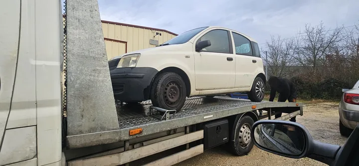 Voiture claire vue de côté sur le plateau d’un camion.