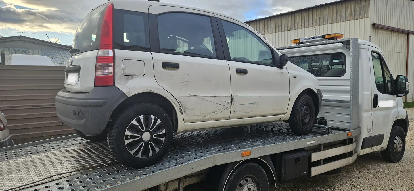 Fiat Panda claire aux portières rayées et enfoncées sur un camion plateau.