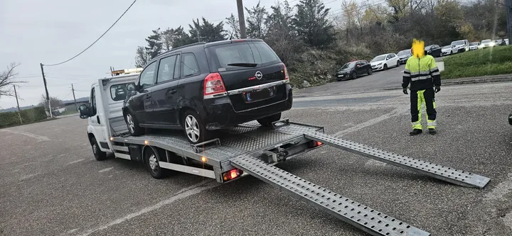 Camion plateau avec ses rampes déployées et une personne à côté du véhicule.