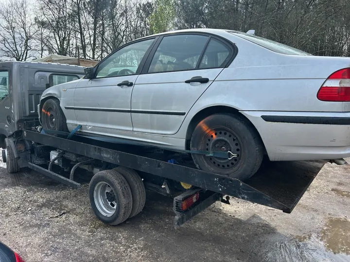 Berline claire sur le plateau d’un camion à roues arrière jumelées.