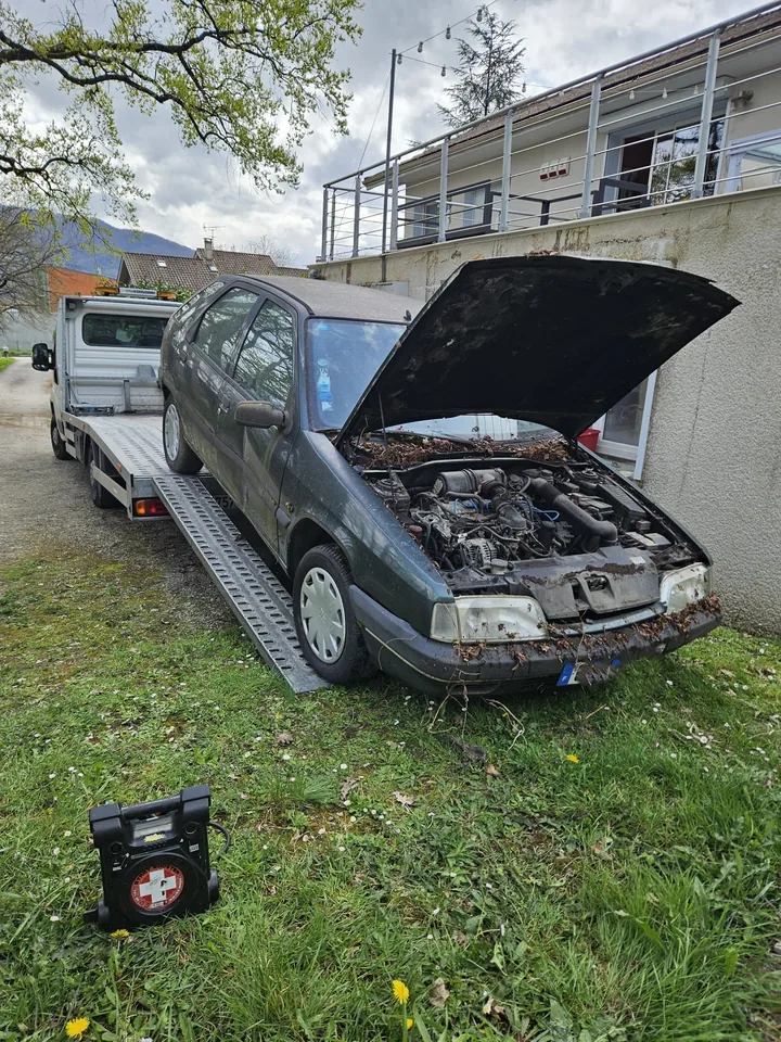 Voiture au capot ouvert sur un plateau, avec sa partie avant visible.