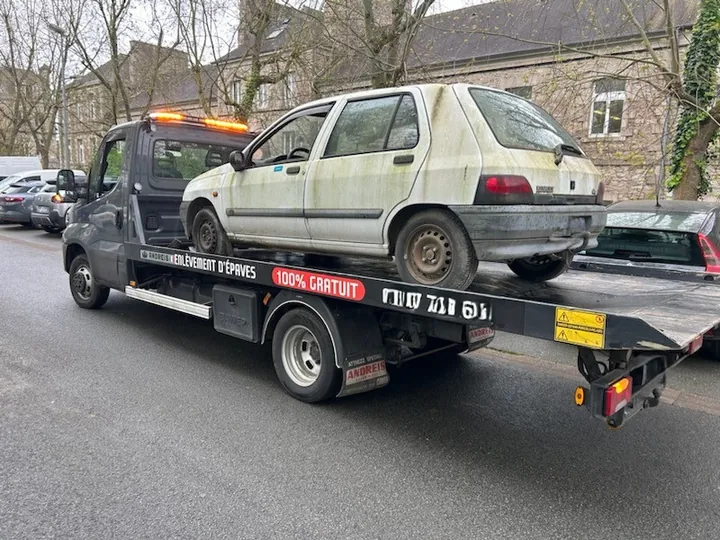 Petite voiture claire à hayon chargée sur un camion plateau.