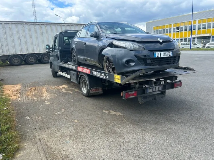 Voiture sombre présentant des dégâts sur sa partie avant, installée sur un plateau.