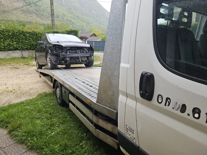 Voiture sombre sans plusieurs éléments avant sur un plateau abaissé.