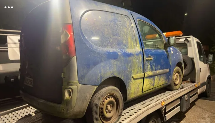Flanc et arrière d’une fourgonnette bleue chargée sur une dépanneuse.