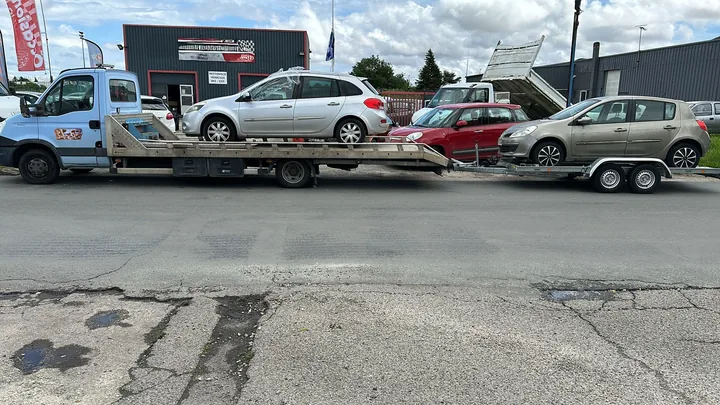 Camion plateau portant une voiture et remorque portant une seconde voiture.