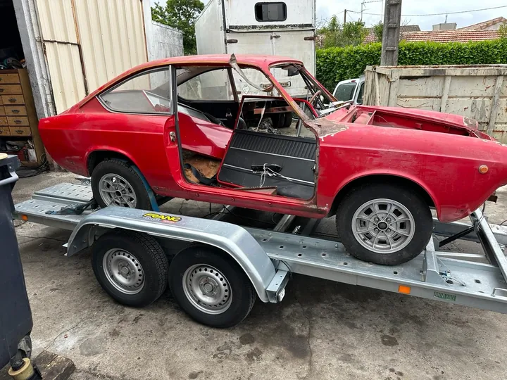 Carrosserie rouge de voiture avec plusieurs éléments absents, installée sur un plateau.
