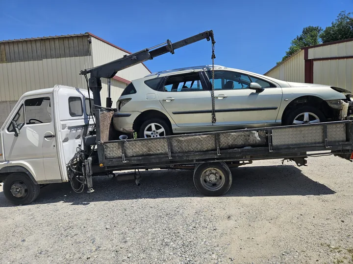 Voiture claire à l’avant incomplet sur un camion équipé d’une grue déployée.