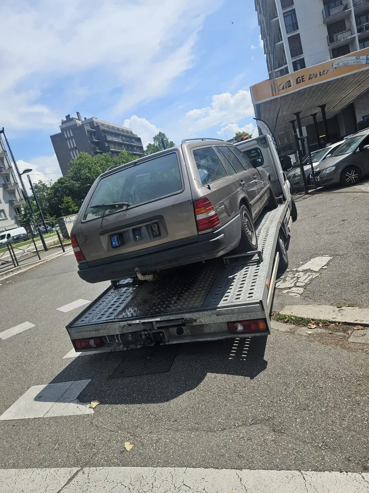 Arrière d’un break ancien sur une dépanneuse au bord d’une rue.