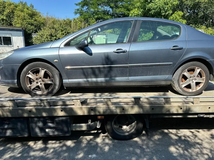 Berline grise à quatre portes de profil sur un plateau métallique.