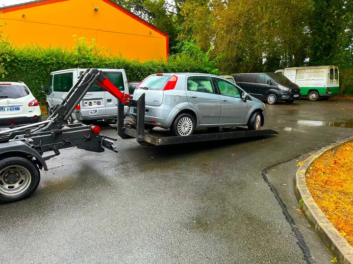 Citadine grise sur une plate-forme métallique portée par un bras de levage.