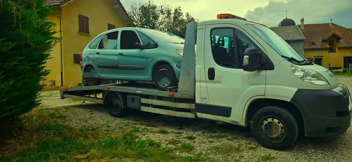 Monospace clair chargé sur une dépanneuse au bord d’une maison.