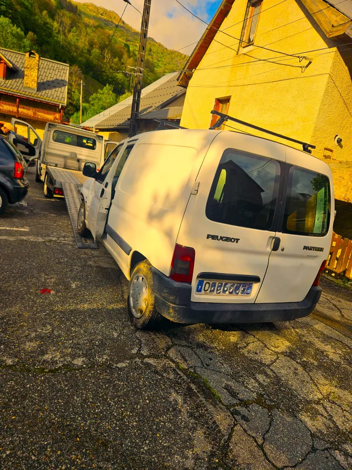 Fourgonnette blanche dans une rue pavée bordée de bâtiments.