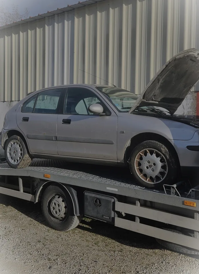 Voiture claire au capot ouvert sur le plateau d’une dépanneuse.
