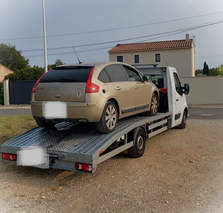 Berline compacte claire chargée sur une dépanneuse blanche.