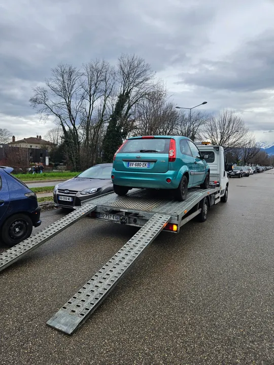 Voiture verte sur un plateau avec les deux rampes déployées vers le sol.