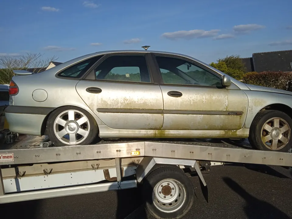 Voiture claire vue de profil sur le plateau d’un camion blanc.