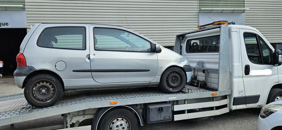 Véhicule clair à carrosserie haute vu de profil sur un camion plateau.