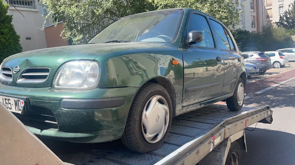 Voiture verte installée sur un plateau, vue depuis son angle avant.