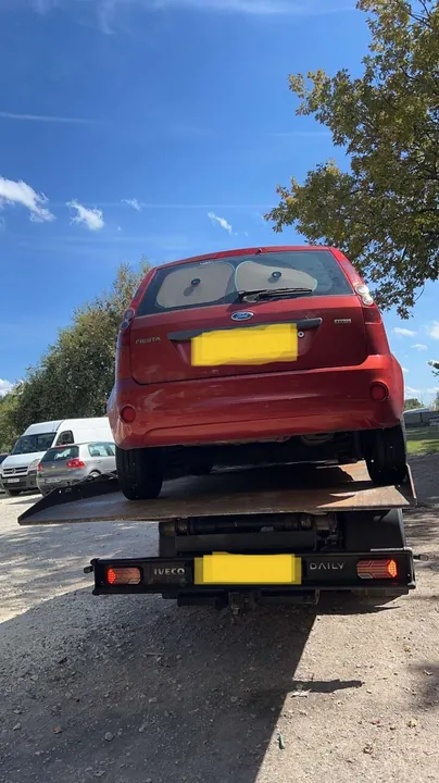 Voiture rouge installée sur un plateau, photographiée depuis l’arrière du camion.